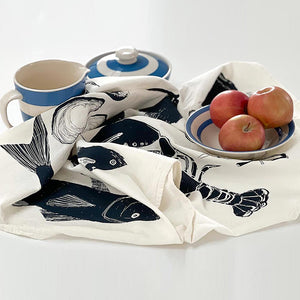 Seafood tea towel with a cup, apples, and plates on a white background