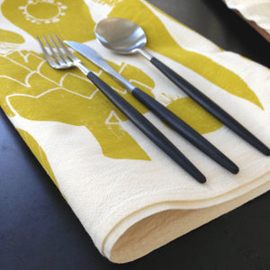 Tea-towel handprinted with Veggie design with cutlery on a black surface