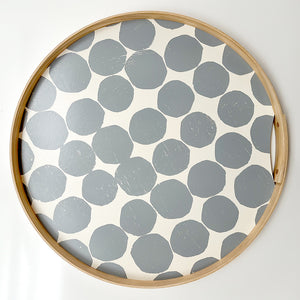 A round Gray printed tray. Hand-printed design featuring PilgrimWaters gray dots on a cotton white background, bound with a natural ash wood edge. The tray is displayed head-on.