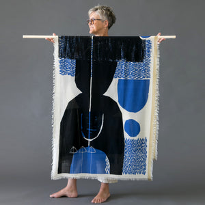 Cotton silk scarf folded in half on a pole held by Susy. The scarf is printed with an abstract design by PilgrimWaters called 'Arrow.'