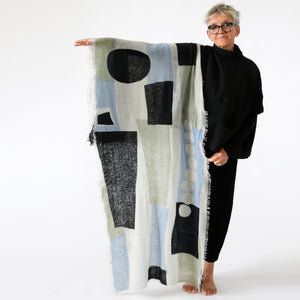 100% cashmere Totem George knitted large scarf being held by Susy. Design by PilgrimWaters. Printed in Nepal.
