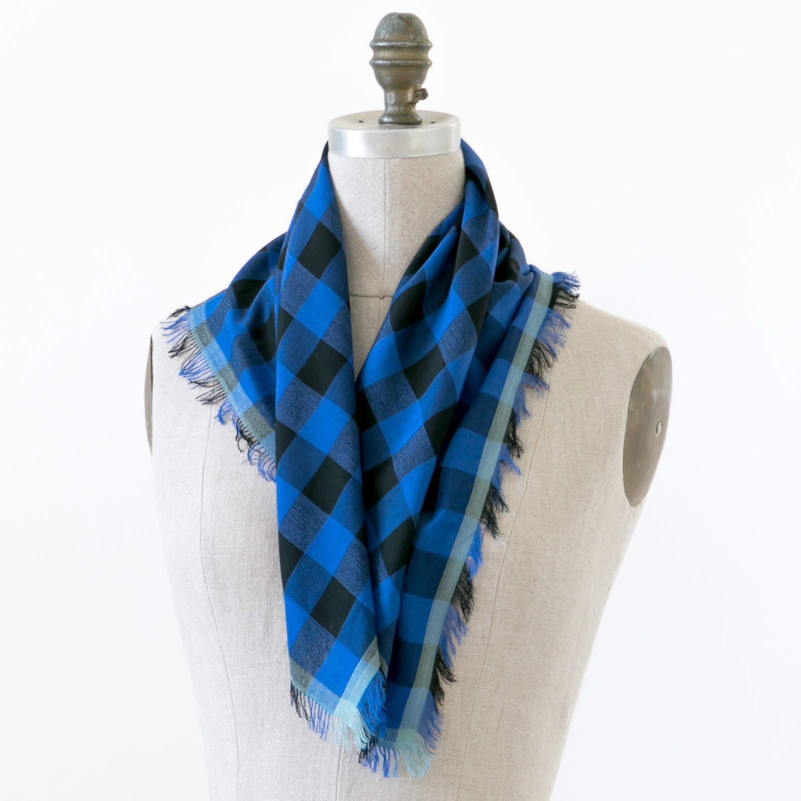 Littles Felix gingham merino wool silk neckerchief draped on a mannequin, showing four-sided fringe — © 2026 PilgrimWaters.