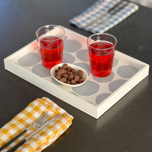 Gray Mini Valet tray with two wine glasses and snacks, on a table with napkins and utensils.