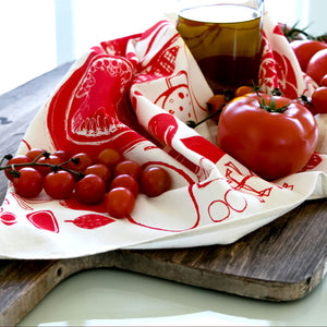 Tomatoes tea towel by PilgrimWaters, still life with breadboard, tomatoes and a bottle of olive oil. Copyright PilgrimWaters 2026.