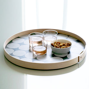 An 18-inch hand-printed round gray-on dark-gray tray styled on a kitchen surface in a brightly lit room.